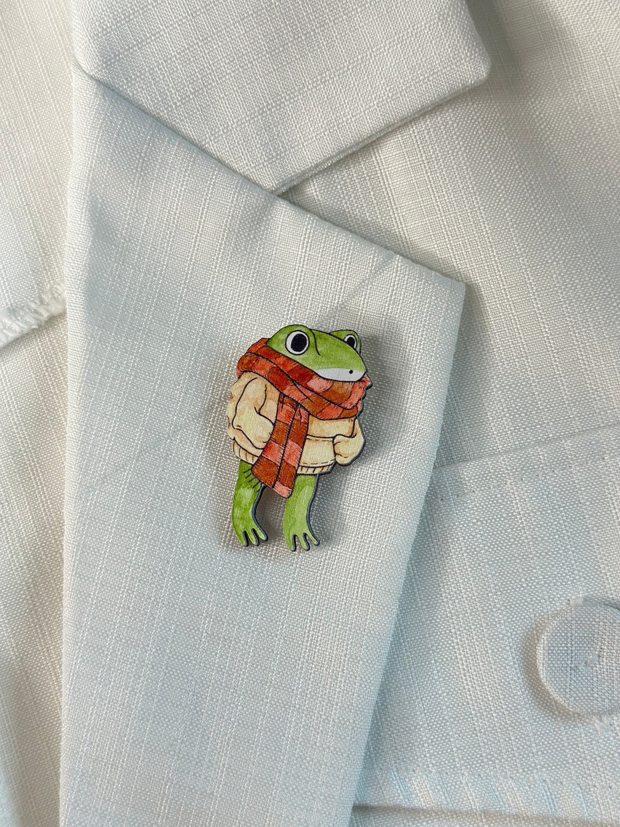 A wooden brooch with a frog and a sweater