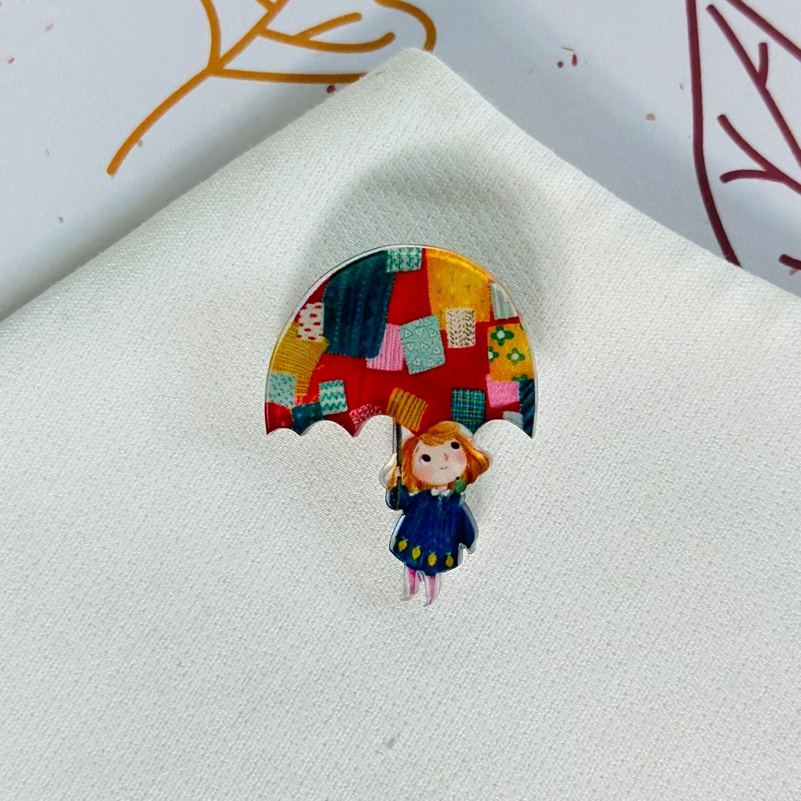 A girl with a colorful umbrella and a glass brooch